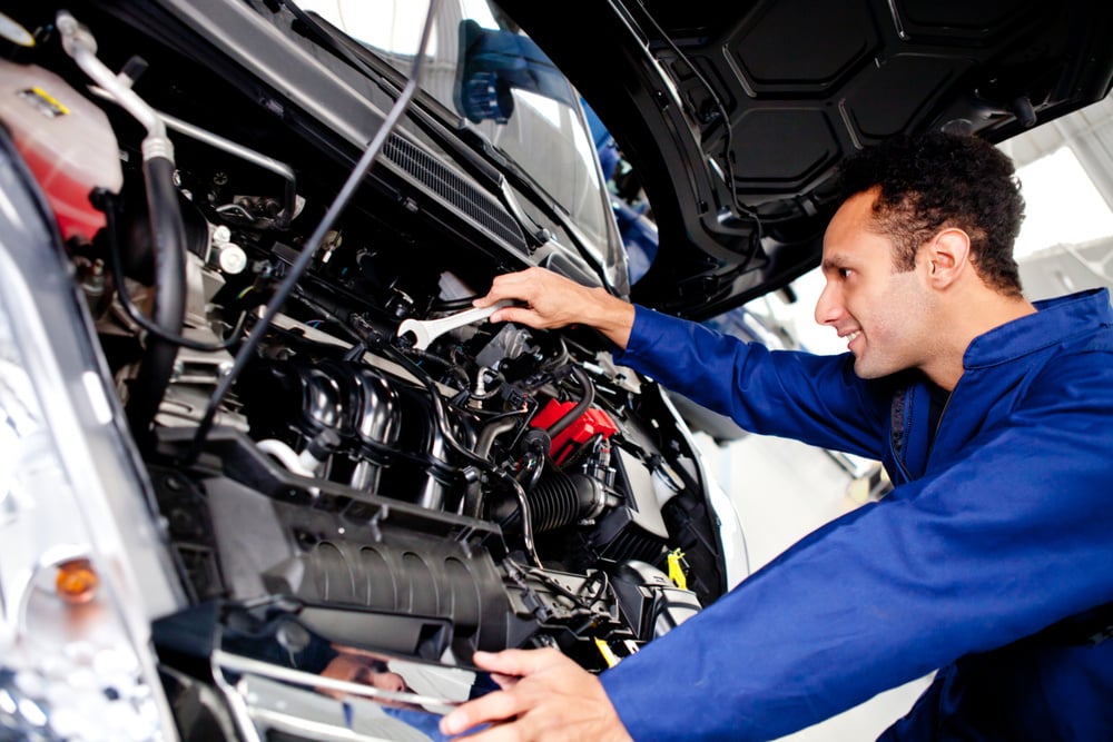 Car mechanic fixing a broken engine at the garage